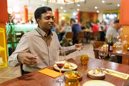 Eshwar gesticulates mid-conversation at a restaurant table
