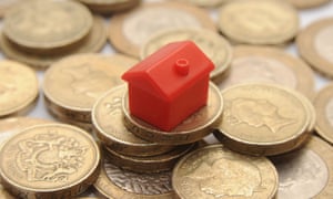 plastic model of a house on a pile of one pound coins