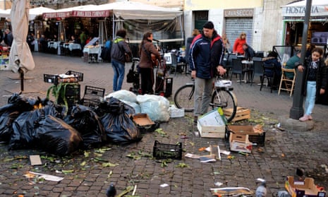 A man looks at a pile of rubbish in a market area of central Rome.
