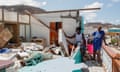 A man and a woman look into her destroyed bedroom in a house that is missing its roof