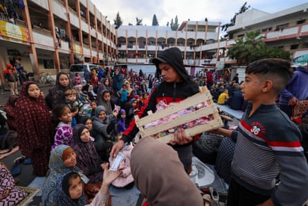 A boy distributes sweets to displaced Palestinians at Eid morning prayer in a school-turned-shelter in Rafah.