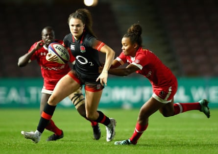 Ellie Kildunne in a black and red England kit making a run during the Old Mutual Wealth Series match at Twickenham while two opponents wearing red and white kits run after her