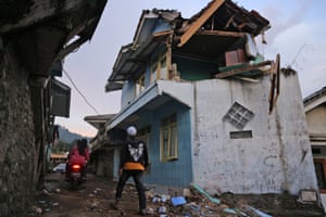 West Java, Indonesia: A man walks past a house damaged by an earthquake in Cianjur