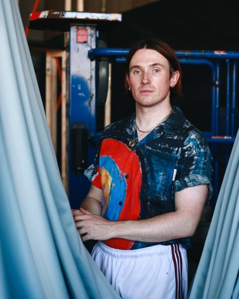 Richard Malone in a workshop, flanked by draped fabric