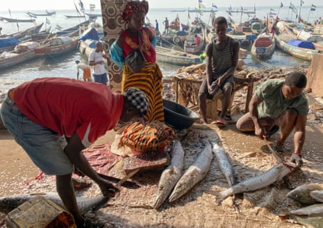 Traders at Tombo market descaling fish.