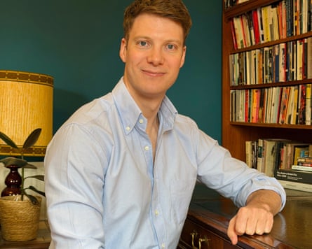 Tom Hulme, historian at Queen’s University Belfast, sets at a desk before a packed bookcase