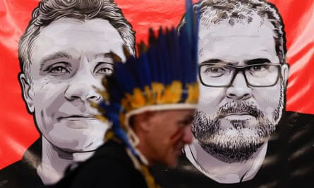 A demonstrator passes a poster of the journalist Dom Phillips and indigenous expert Bruno Pereira 