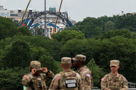 Members of the National Guard stand at the base of the Washington Monument, as construction on a temporary arena that will host the UFC Freedom 250 fight card in June on the South Lawn of the White House appears in the distance, in Washington, D.C., U.S., May 27, 2026.