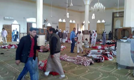 Egyptians walk past bodies following a gun and bombing attack at the Rawdah mosque.