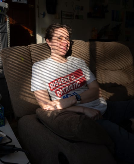 A woman sitting on a couch in bright sunlight and shadows from Venetian blinds.