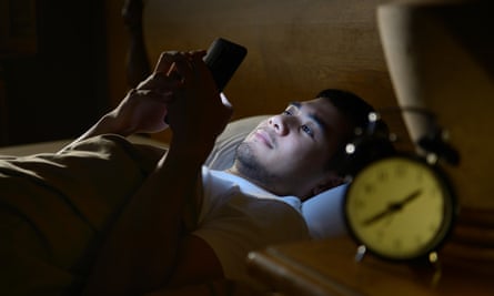 Young man using smartphone in bed