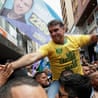 Presidential candidate Flavio Bolsonaro rides on a man's shoulders during a campaign rally.