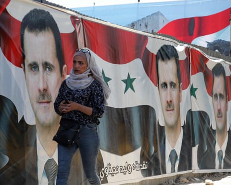 People walking past campaign billboards of Bashar al-Assad
