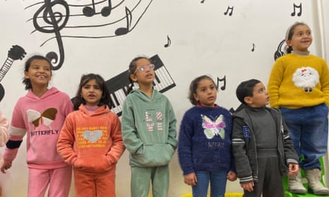 Children stand in front of a mural of musical notes
