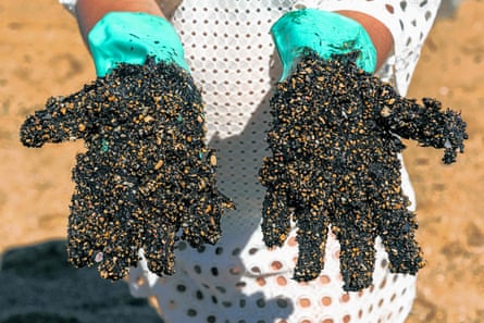 A volunteer shows his protective gloves encrusted with crude oil spilled at Praia de Busca Vida beach in Camacari, Bahia state
