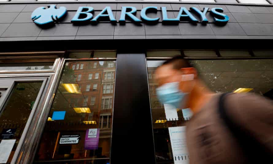 A pedestrian wearing a face mask walks past a branch of a Barclays bank