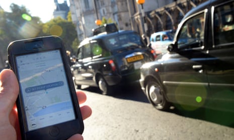 Uber app open on a phone next to line of black cabs