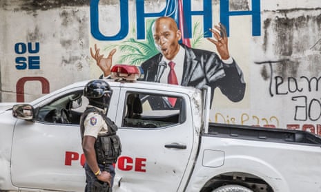 A police officer stands by a wall painted with a mural of late Haitian president Jovenel Moise, who was killed in July 2021.