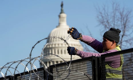 A worker removes razor wire from the top of security fencing on 20 March 2021, as part of a reduction in heightened security measures taken after the 6 January attack on the US Capitol in Washington DC.
