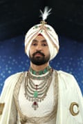 Diljit Dosanjh wearing a white and gold outfit with many jewels