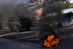 A military vehicle drives past tires set on fire by residents to protest against the operation