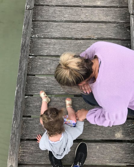 A woman sits with a small child on a boardwalk