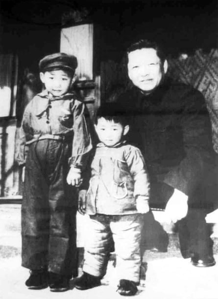 Black and white photo of Xi Jinping standing with another child while his father crouches next to them