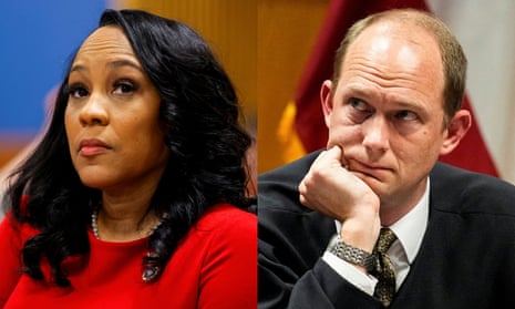 a black woman with black hair in a red shirt and a white balding man in a suit and black robe