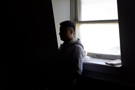 Silhouette of a man standing next to a window inside a dairy barn.