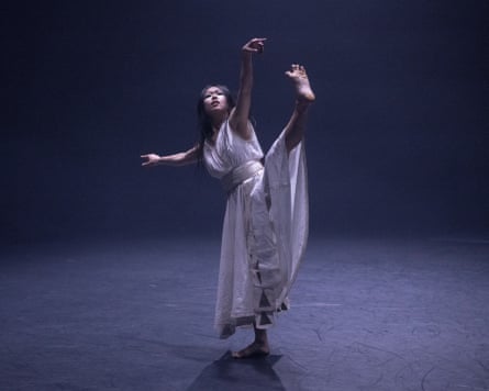 A woman in white dancing alone on stage.