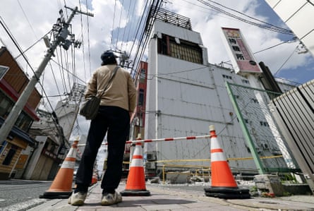 A man looks up at a damaged building