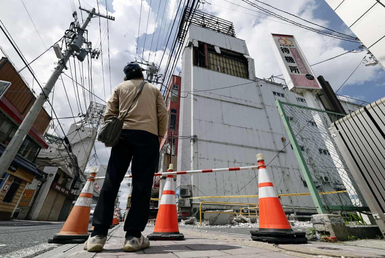 A man looks up at a damaged building