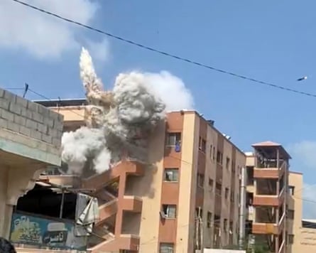 Smoke rises from the corner of a hospital building as another missile flies towards it