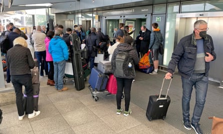 People queue with luggage at Heathrow airport.