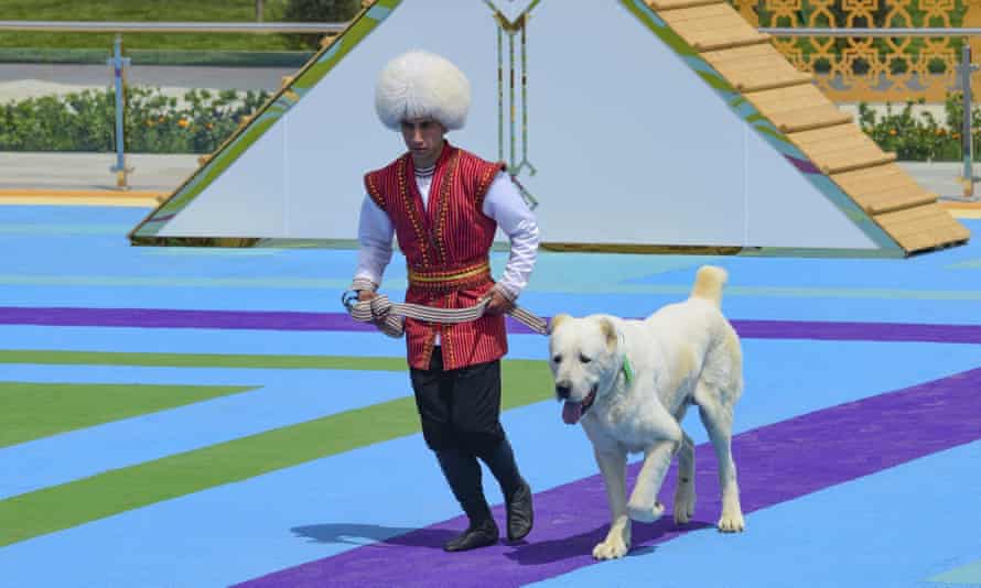 Un hombre vestido con traje nacional corre con su perro pastor de la guardia fronteriza Alaba en Ashgabat, Turkmenistán, el domingo 25 de abril de 2021.