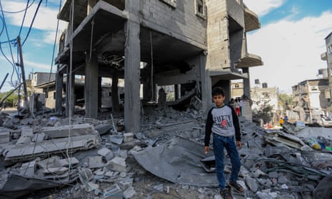 A young boy stands in front of a home destroyed by Israeli airstrikes on 3 January 2024 in Rafah, Gaza.