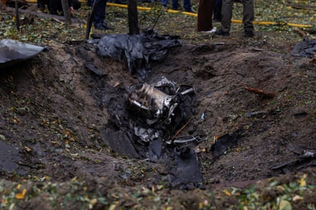 Drone wreckage lies inside a muddy crater at a Kyiv strike site
