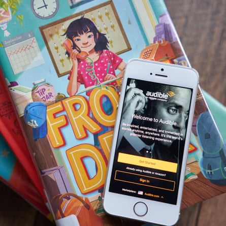 Audible mobile app login page is seen on a smartphone atop library books.