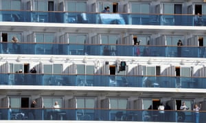 Passengers of the Diamond Princess cruise ship gesture from their balcony