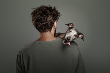 A dog looks over a man’s shouldler