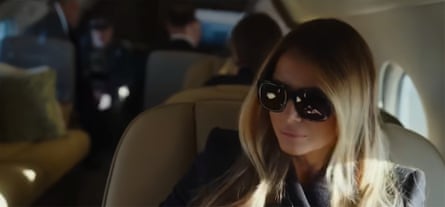 A woman sits in a plane wearing sunglasses