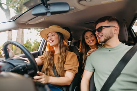 Three young friends travelling by car, two in the front