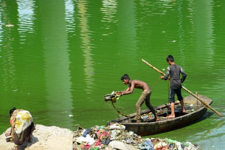 Indian workers collect and remove trash with a boat as they take part in the cleaning of the Sabarmati river in Ahmedabad on May 21, 2019.