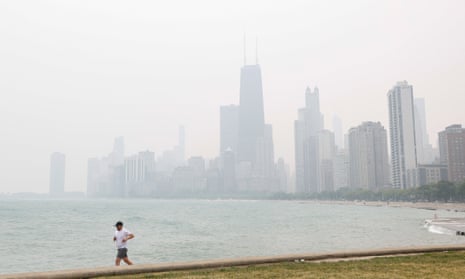 A jogger runs along the shoreline of Lake Michigan with heavy smoke from the Canadian wildfires in the background on Tuesday in Chicago, Illinois.