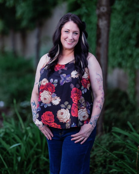 Shauna Castaner smiling at the camera, standing on a grass verge next to a path with her thumbs in her pockets, wearing a sleeveless floral top and blue jeans