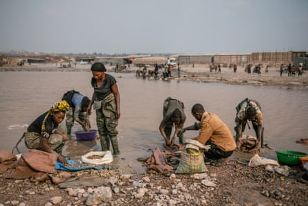 African women standing in shallow water cleaning small rocks, which are being deposited in sacks