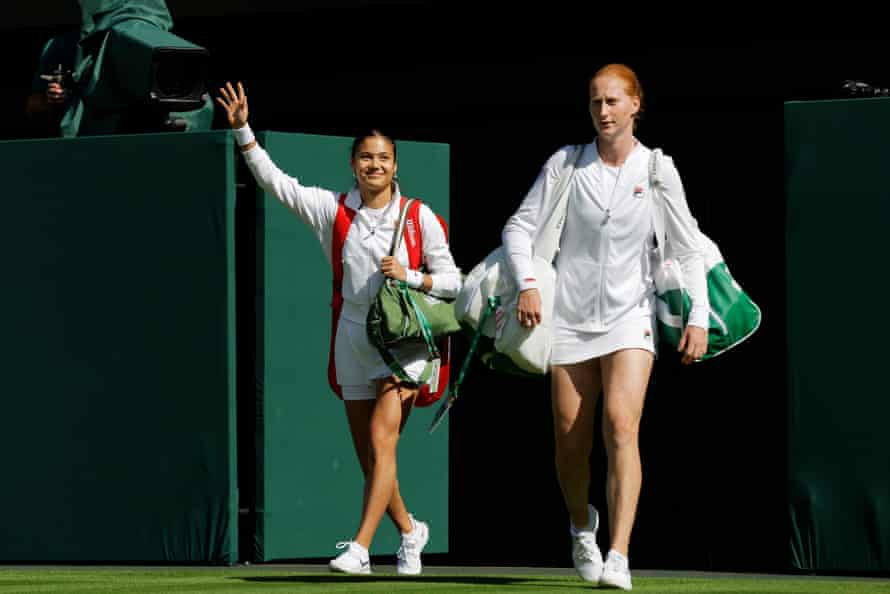 Emma Raducanu and Alison van Uytvanck (right) enter the court ahead of their women’s singles tennis match.
