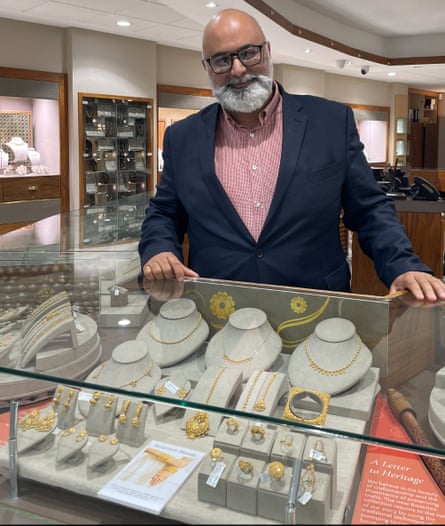 Jayant Raniga, the owner of PureJewels in London, stands behind a display of gold jewellery.