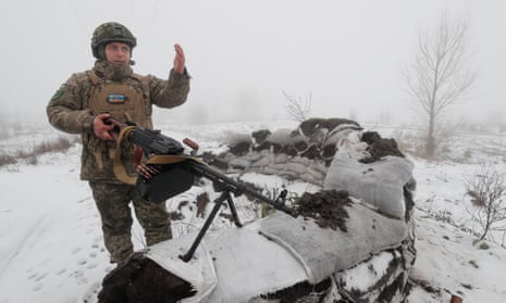 Vasyl, a member of Ukraine’s territorial defences, holds a mounted machine gun at a position made of sandbags in a snowy landscape
