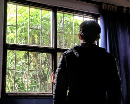 Juan, a boy with his back to camera looking out of a window